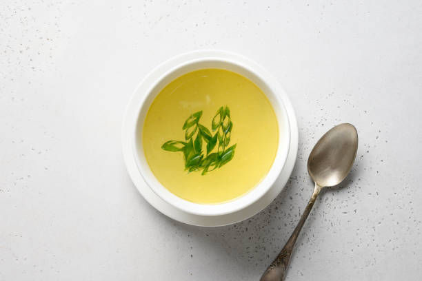 istock Chicken broth with greens in white bowl over white table. Copy space. 1251572984