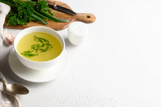 istock Chicken broth with green onion in white bowl on white table. Copy space. 1251572989