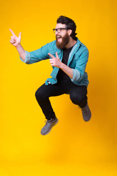 istock Excited bearded man is jumping high showing cool gesture 1251573599