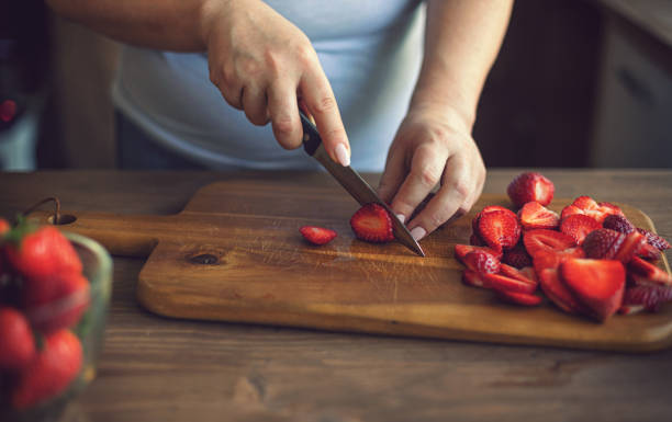 istock Young Women Cutting Fresh Strawberries 1251575208
