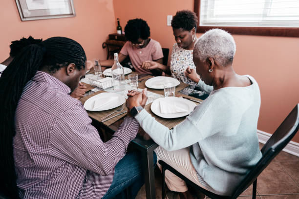 istock Whole family sitting and praying holding hands together before dinner 1251575321