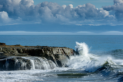 Huge ocean waves crashing on rocky pacific shore.\n\nTaken in Santa Cruz, California, USA
