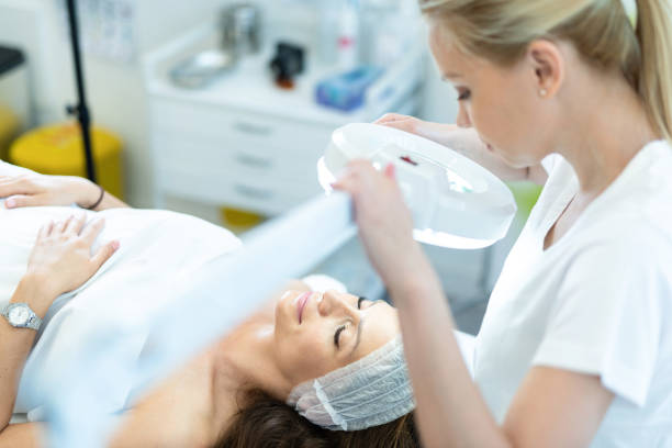 istock Cosmetologist Inspecting Young Woman's Skin Close up. 1251576525