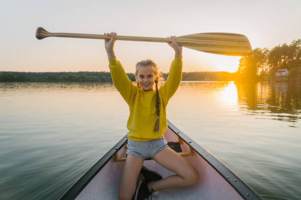 A Portuguese woman canoeing on a lake of the Laurentians,  Quebec, during a sunrise of summer.