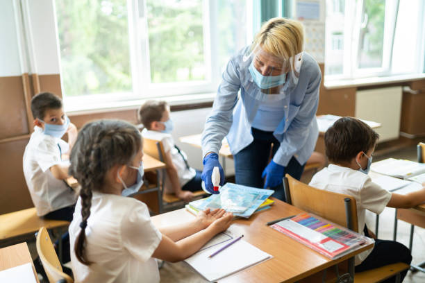 istock COVID-19. Disinfecting hands in classroom 1251580703