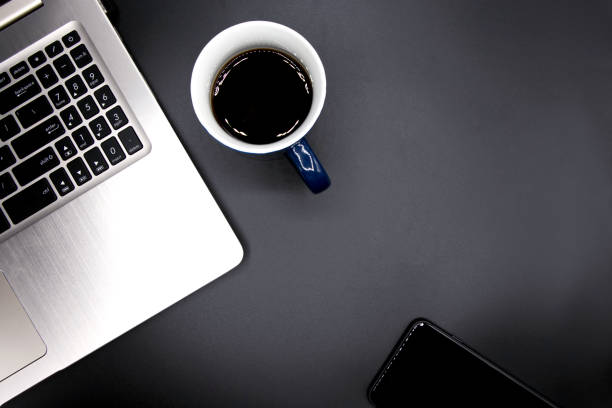 istock Laptop computer with coffee cup and smart phone on old black vinyl office desk texture,Top view with copy space,Workspace background 1251581837
