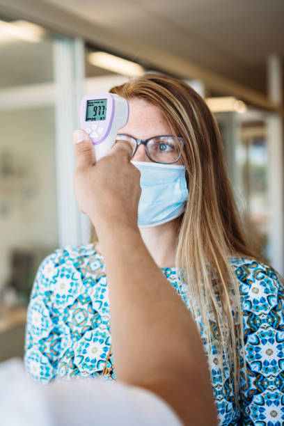 istock Woman Has Temperature Taken By Office Worker Wearing Mask 1251582973