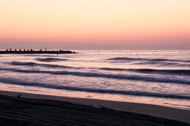 istock Sunrise on the beach, jetty with fishermen 1251583485