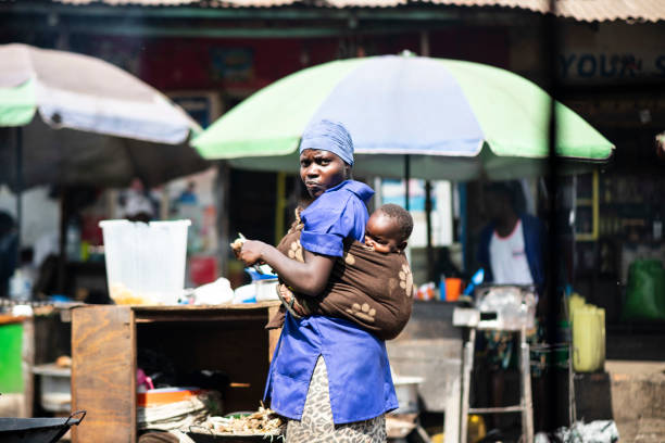 Woman with her child prepares food at a market of Kampala, Uganda. stock photo