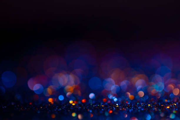 istock Festive bokeh glitters background, abstract blurred backdrop with circles,modern design wallpaper with sparkling glimmers. Black, blue and golden backdrop glittering sparks with blur effect. 1251584906
