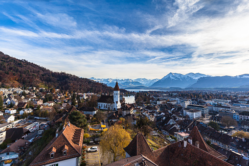 Stunning aerial panorama view of Thun cityscape and Aare river flowing to Lake Thun from Thun castle, with Swiss Alps mountain peaks on Bernese Oberland in background, a sunny autumn day, Switzerland