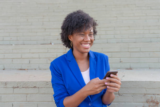 istock Young woman laughing while using mobile at street 1251587324