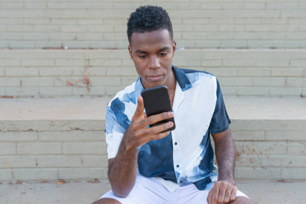 istock Young man sitting on staircase and using mobile at street 1251588022
