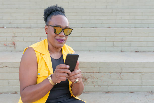 istock Senior businesswoman using cellphone sitting on staircase 1251588084
