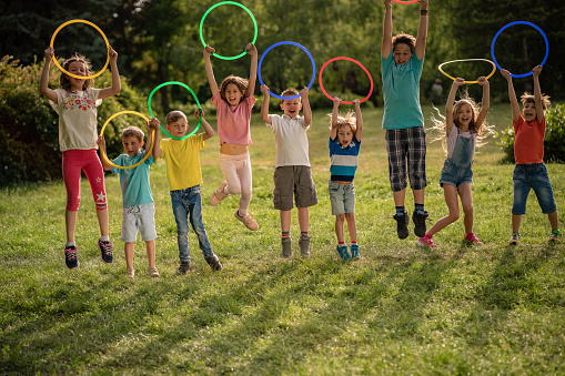 Group of children jumping with plastic hoop in hands