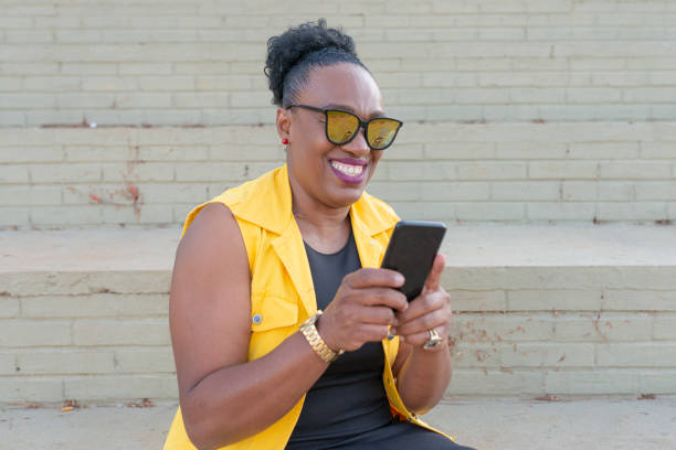 istock Senior business woman laughing while using cell phone sitting on staircase 1251588118