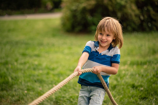 Cute little boy plays Tug-of-war in public park
