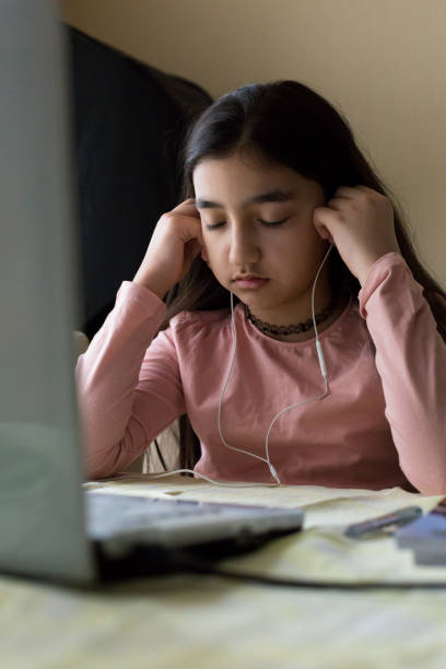 istock Young girl thinking over a problem at the table with laptop at home schooling, online virtual classroom video conference, distant education. Internet network connection problem, unhappy child. 1251591591