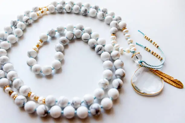 A close up shot of a white and gold mala bead necklace