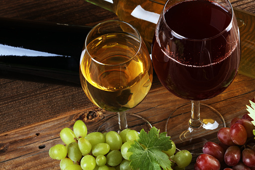 red Wine glass and white wine with grapes on rustic background