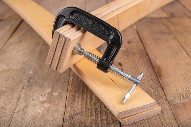 istock Carpentry clamp used for gluing wood. Carpentry accessories in a home workshop. Workplace - carpentry workshop. 1251594347