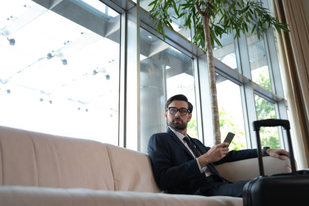 istock Businessman thoughtfully watching raindrops on window glass from a hotel lobby 1251596515
