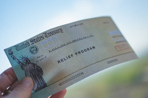 istock COVID-19 economic Stimulus check on blurred USA flag background. Relief program concept. 1251598486