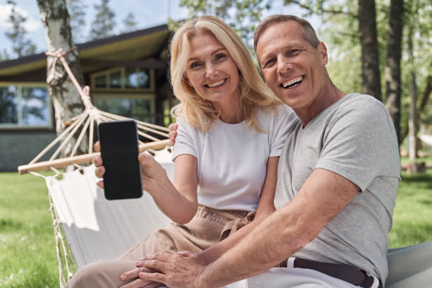 istock Happy mature spouses using smartphone in green yard 1251603495