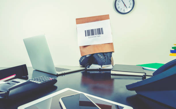 Young boy in a business suit with a barcode bag on his head. Young boy in a business suit with a barcode bag on his head. He is sitting in an office with a laptop computer and other technology. Just a number, hiding, no individuality concept embarrassment unrecognizable person wearing a paper bag human head stock pictures, royalty-free photos & images