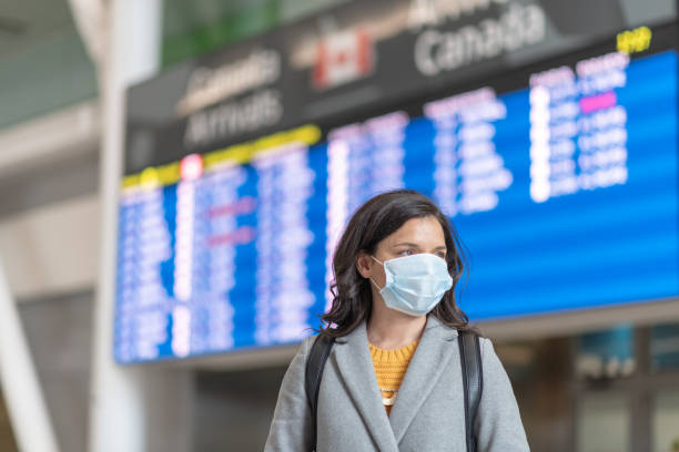 Travels bans during the pandemic A solo travellers flight has been cancelled. She is standing in front of the departures board. She is wearing a protective face mask. Travelling during the COVID-19 pandemic. citizenship photos stock pictures, royalty-free photos & images