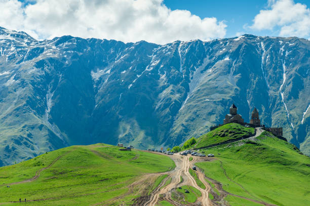 landschaft mit blick auf das wahrzeichen gergeti - dreifaltigkeitskirche auf dem hintergrund der malerischen berge mit verschneiten gipfeln, georgien - kazbek stock-fotos und bilder