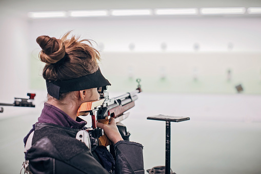 One girl, teenage girl on rifle shooting training indoors.