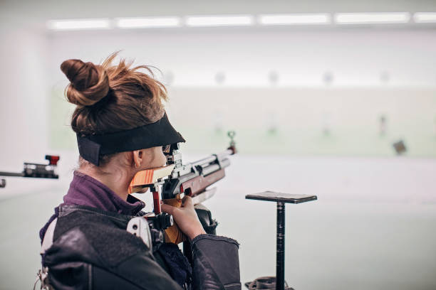 Teenage girl on rifle shooting practice One girl, teenage girl on rifle shooting training indoors. target shooting stock pictures, royalty-free photos & images