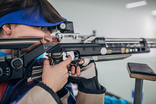 One girl, teenage girl on rifle shooting training indoors.