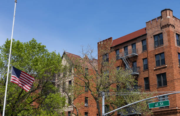 half mast american flag and a row of old brick residential buildings in sunnyside queens new york - sunnyside fotografías e imágenes de stock