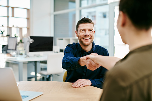 Cropped shot of two young businesspeople shaking hands during a meeting in an office