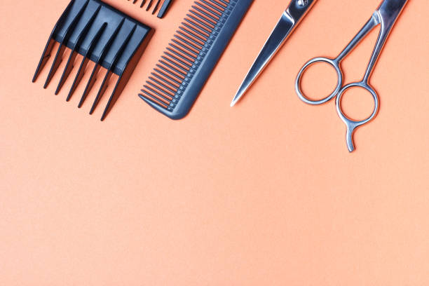 Hairdressing tools, scissors and comb on an orange background, copy space