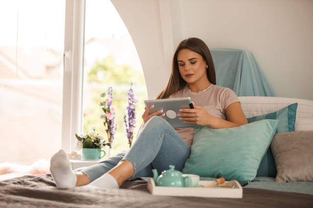 istock Young woman relaxing on the bed and using her digital tablet 1251633325