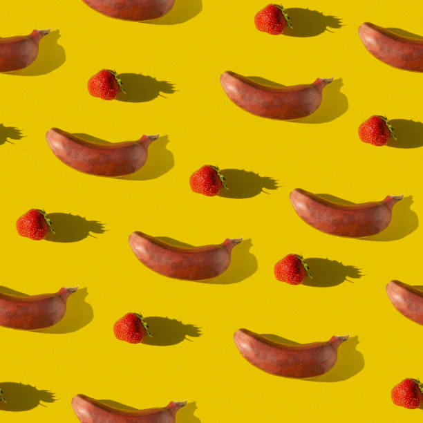istock Creative geometric seamless pattern with fruits. Repeating banana and strawberry on a yellow background. 1251636416