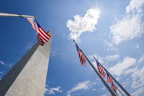 National flag of The United States of America with bright sunny shine in the background. Location - Washington DC - The George Washington Monument