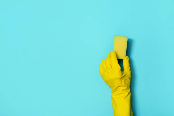 istock Hand in glove holding microfiber cleaning cloth, sponge on blue background. Copy space. Cleaning service concept. Spring general or regular clean up. Commercial cleaning company concept. 1251656753