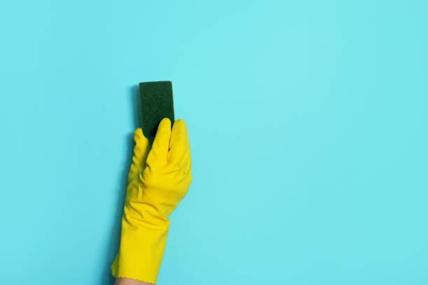 istock Hand in glove holding microfiber cleaning cloth, sponge on blue background. Copy space. Cleaning service concept. Spring general or regular clean up. Commercial cleaning company concept. 1251656763
