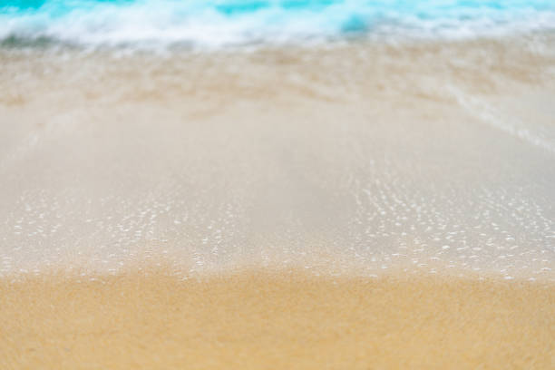istock close up sand beach with blue sea wave background 1251657105
