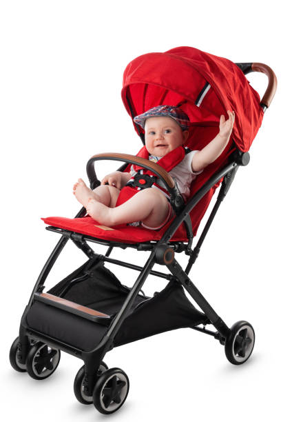 Happy cute baby boy in red pram ready for a summer walk