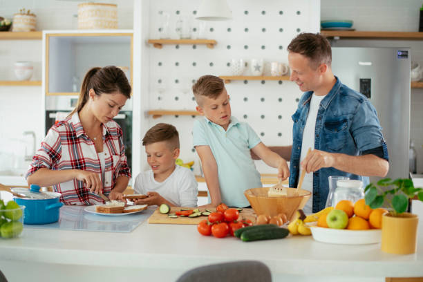istock Mother and father preparing breakfast with sons. 1251658868