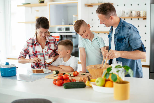 istock Mother and father preparing breakfast with sons. 1251658869