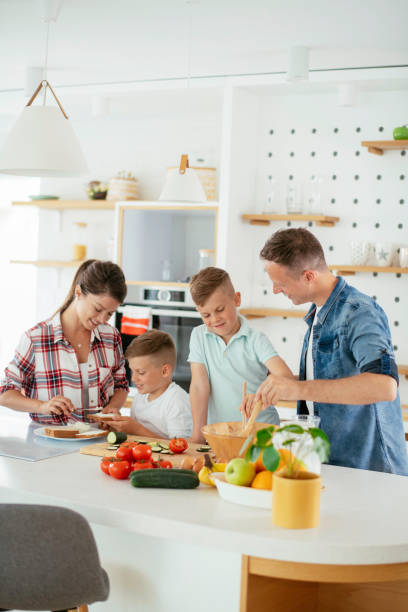 istock Mother and father preparing breakfast with sons. 1251658880