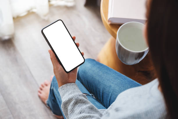 istock a woman holding mobile phone with blank desktop screen while drinking hot water in bed room 1251661458