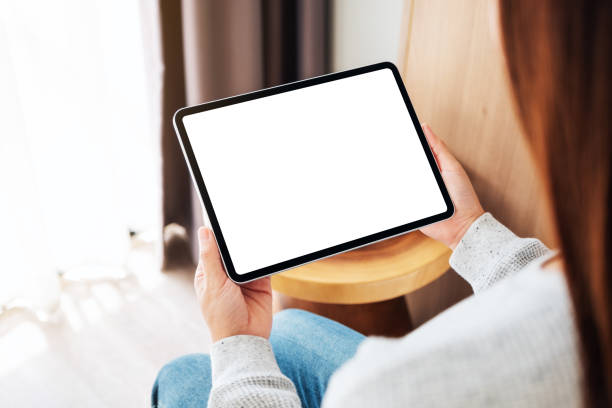 istock a woman holding black tablet pc with blank desktop white screen while sitting on a cozy white bed at home 1251661477