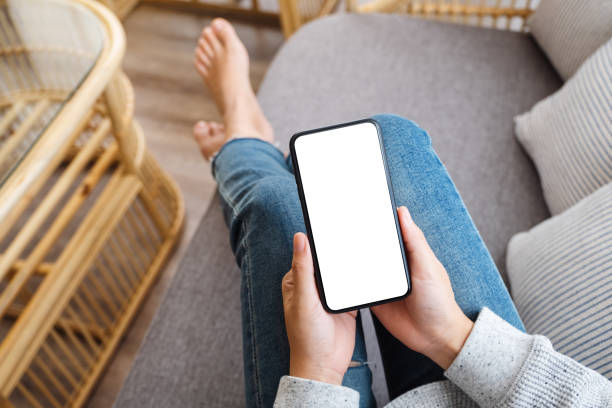 istock a woman holding mobile phone with blank desktop white screen while lying on a sofa at home 1251661486